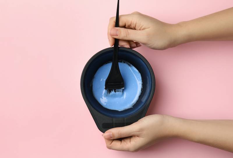 woman preparing dye for hair coloring on pink background